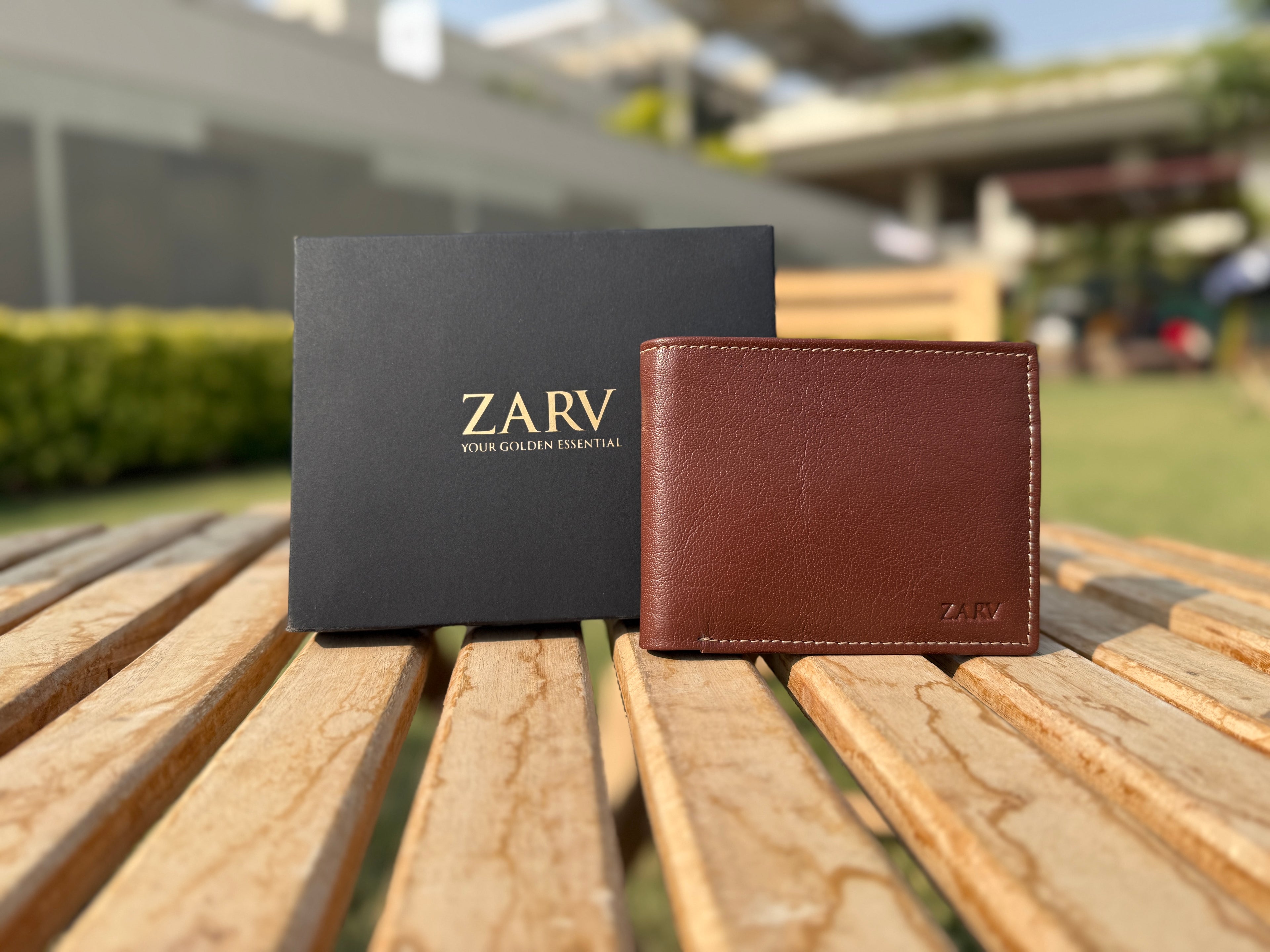 Brown leather wallet with 'ZARV' branding on a wooden surface outdoors.